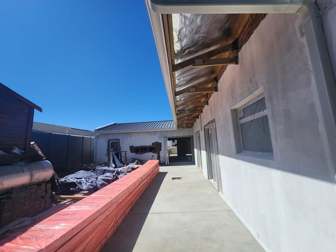 Completed eaves, gutters and a cast concrete walkway alongside the plastered house
