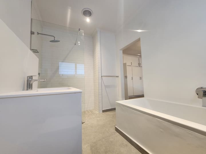 White bathroom with a walk-in shower, subway tiling, built-in bath and a frameless glass screen