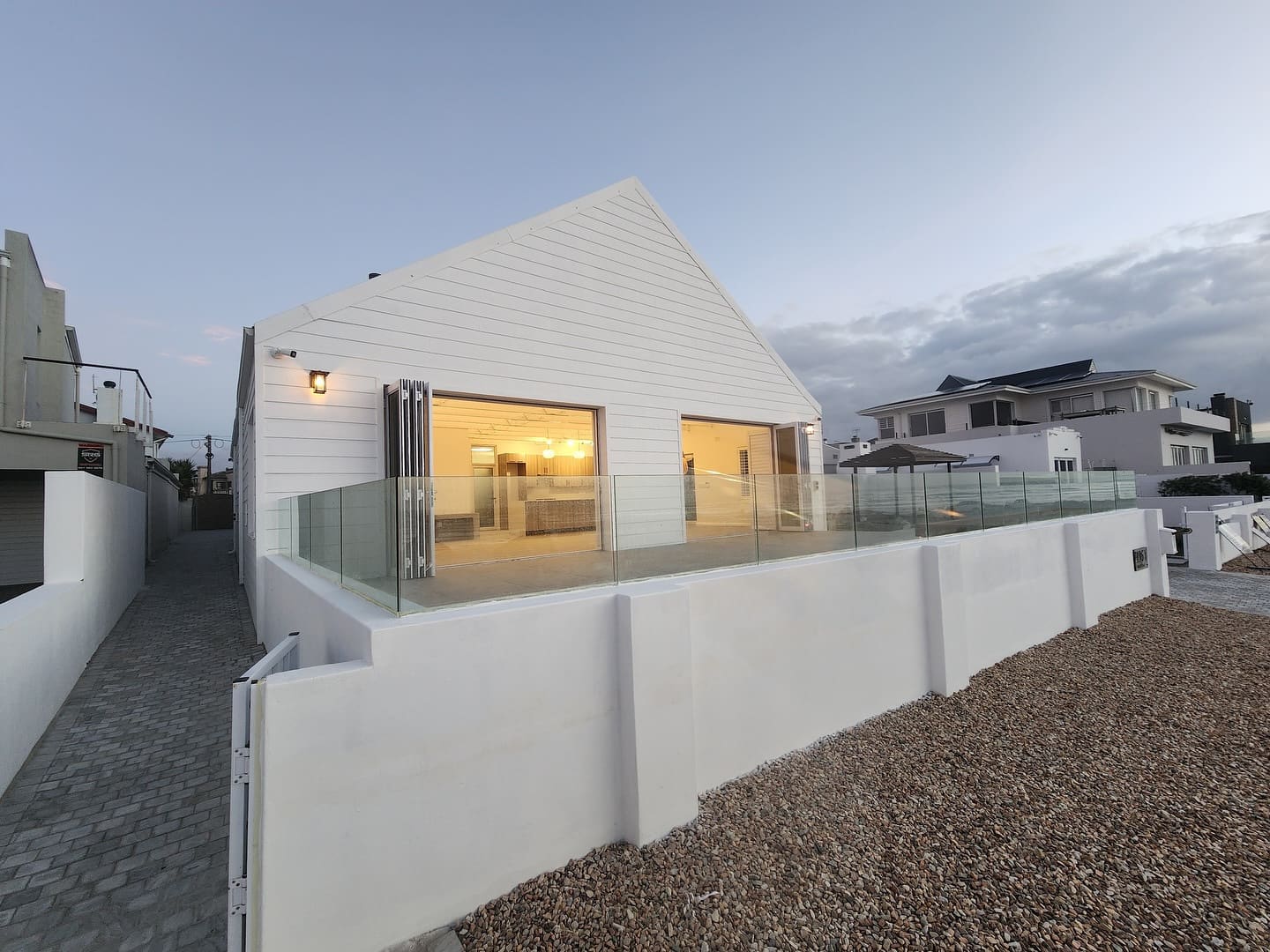 Coastal home exterior with glass balustrade at dusk